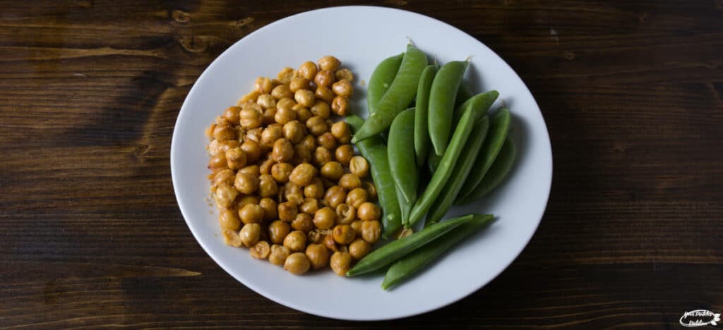 A plate holding a snack size serving of chickpeas and snow peas