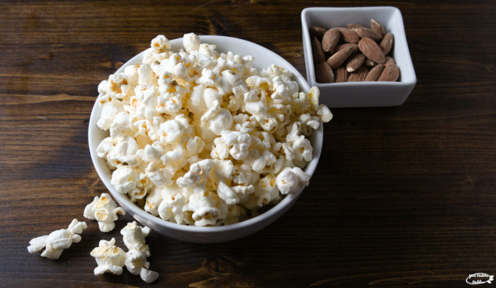 A bowl of popcorn with a side of almonds.