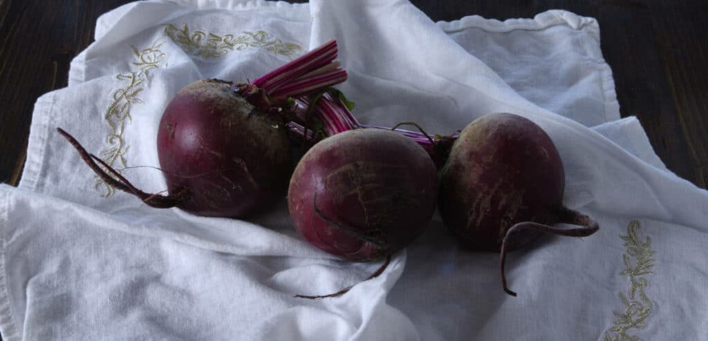 A bunch of raw beets set on a white table cloth