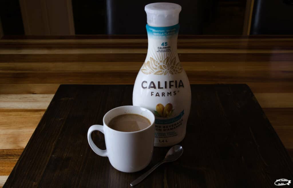 A bottle of Califia Farms Almond Beverage with a cup of coffee.