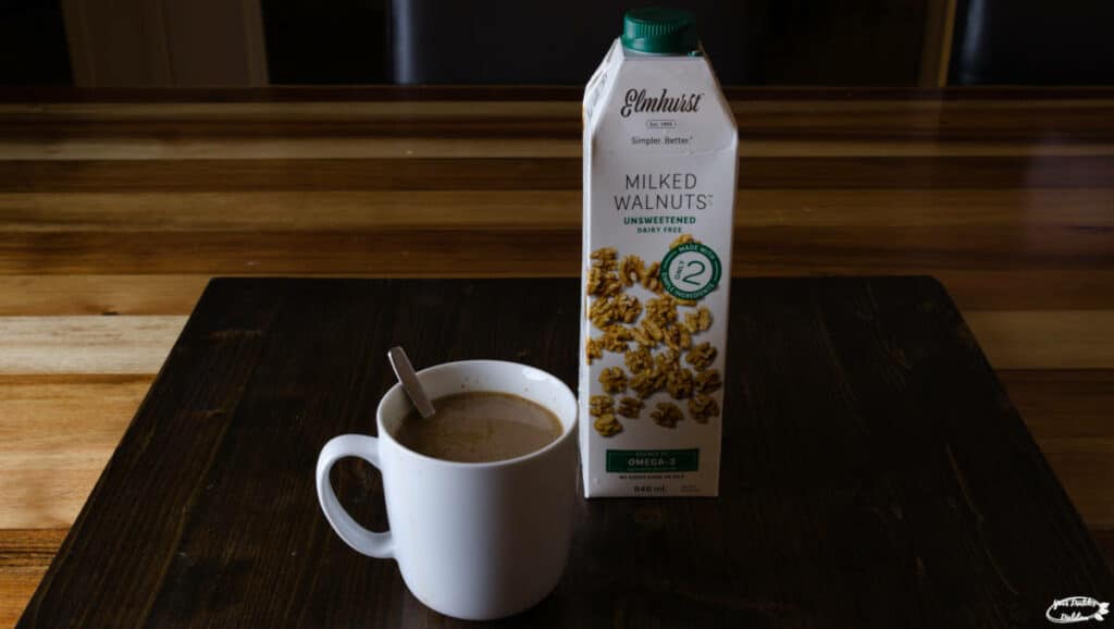 Elmhurst Unsweetened Walnut milk with a cup of coffee