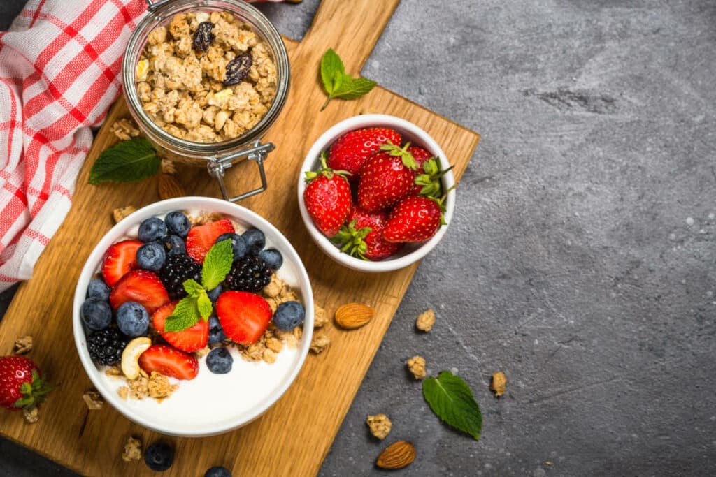 A board with granola made with berries and yogurt.
