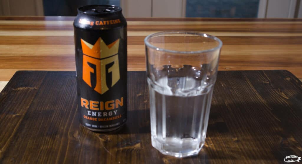 An image of a can of Reign energy drink and a glass of it beside it.